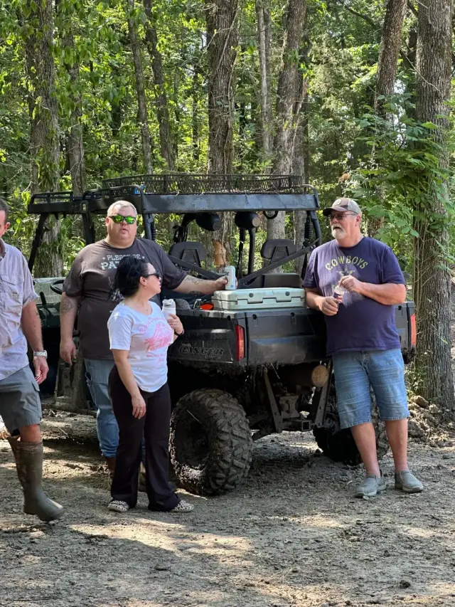 Friends taking a break around a Polaris Ranger with a cooler.