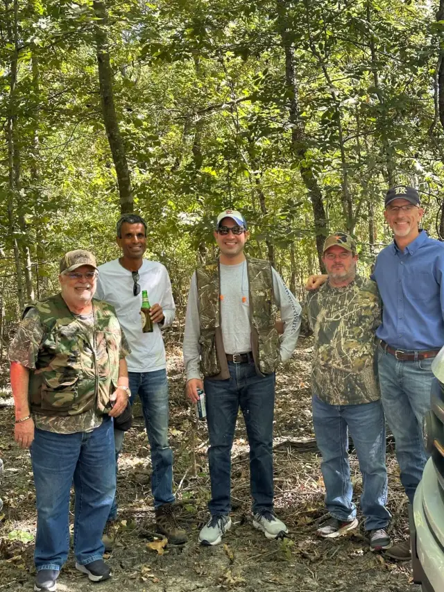 Five friends standing together on a wooded trail.