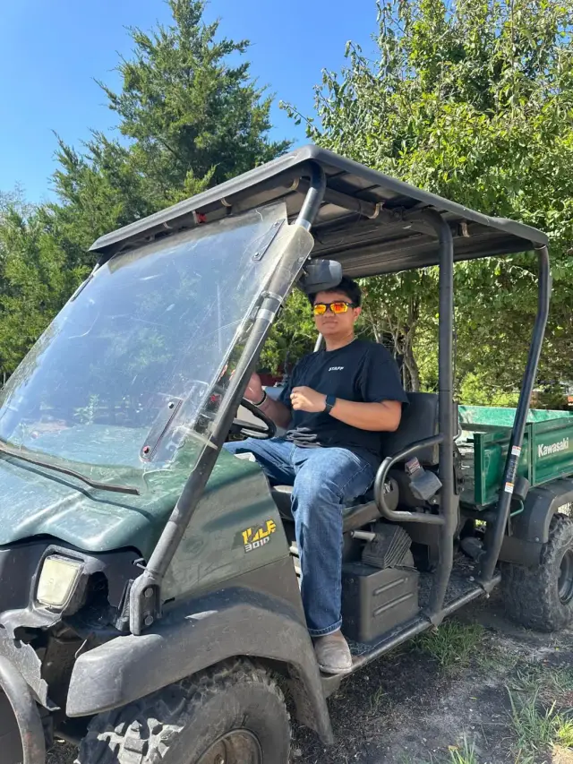 A staff member at the wheel of a green Kawasaki Mule.